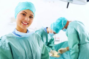 A portrait of a medical assistant while an operation takes place in the background.